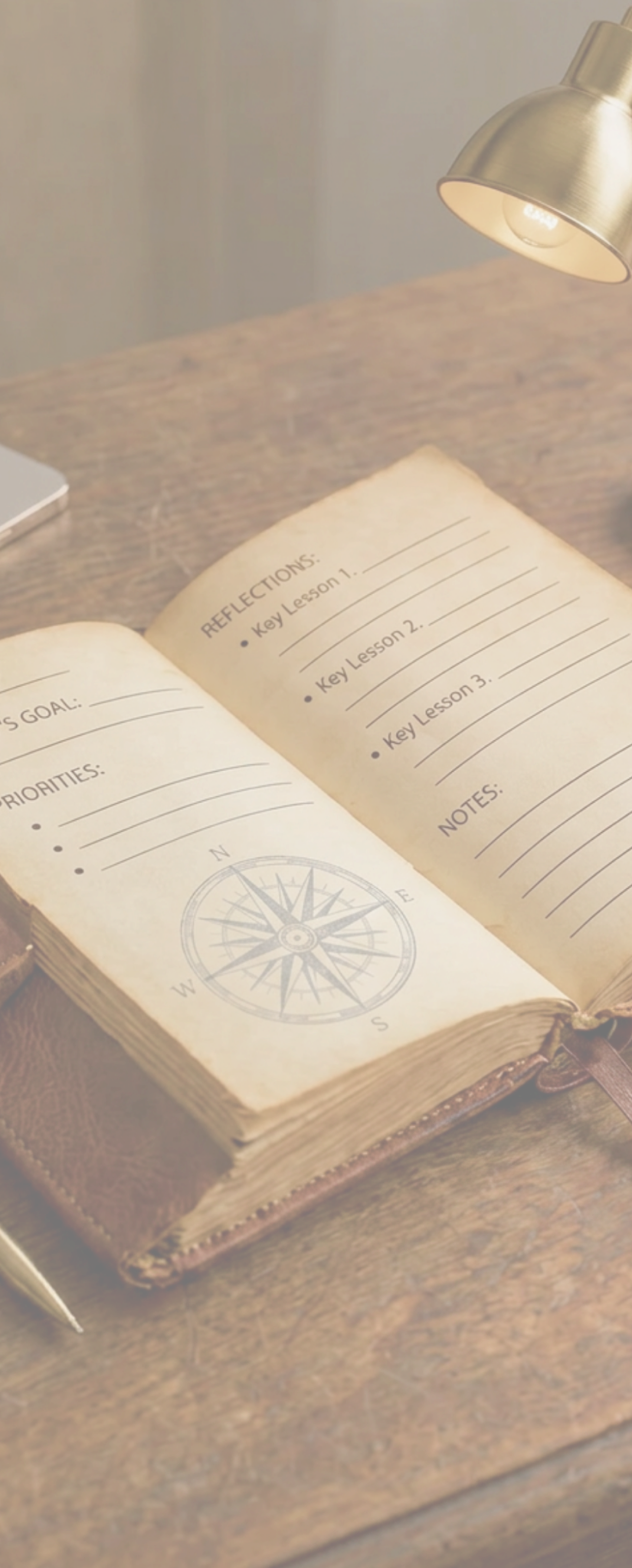 Open journal with compass rose under a desk lamp